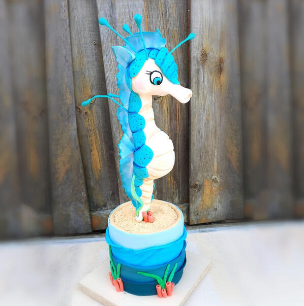 Grote taart van een wit met blauw zeepaardje op de bodem van de zee.